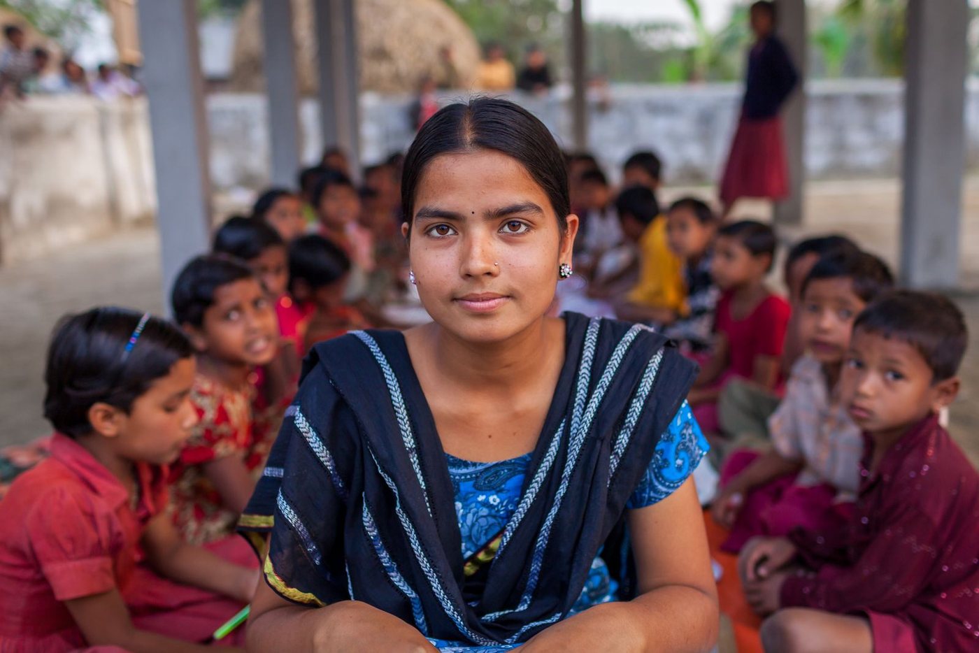 A teacher sitting with her students in an outdoor classroom